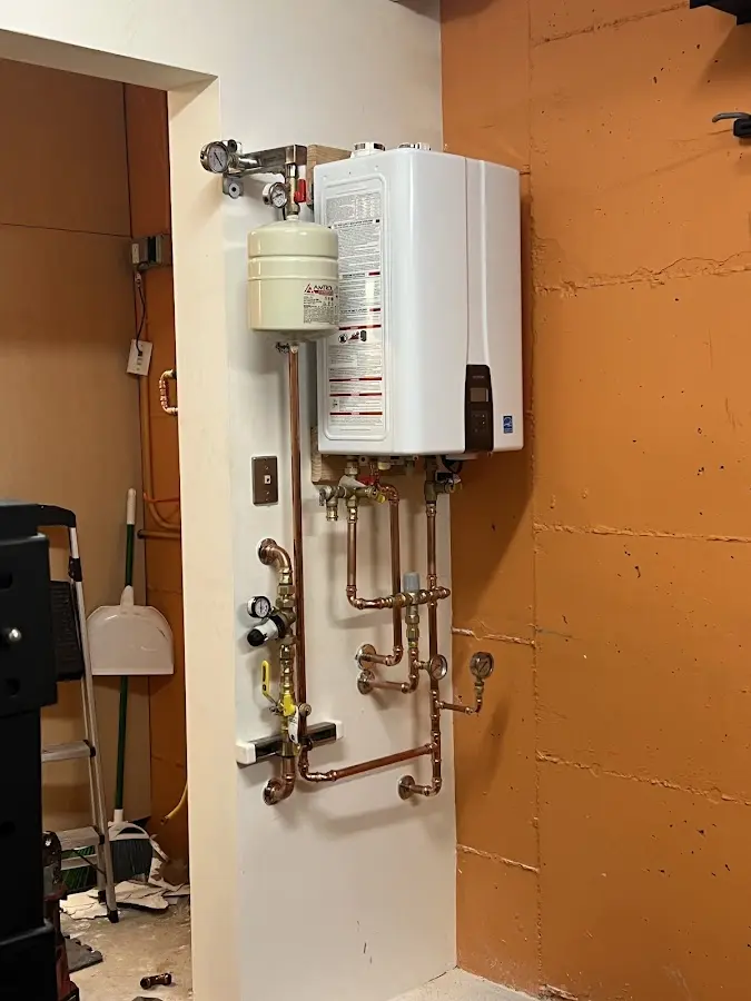 Plumbing technician inspecting water heater connections in Statham